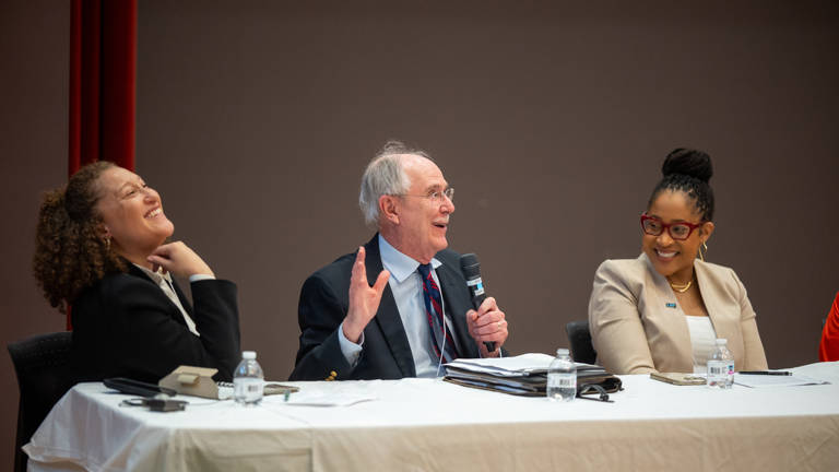 Leah Aden, Jack Boger, and Karla McKanders sitting at a table and smiling during a panel discussion.