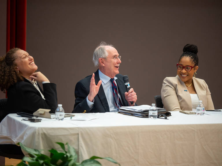 Leah Aden, Jack Boger, and Karla McKanders sitting at a table and smiling during a panel discussion.