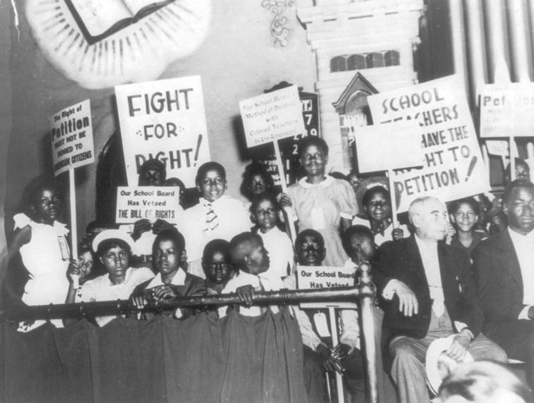 Black-and-white photo of Black schoolchildren holding signs of protest against the school board's treatment of Black teachers in Norfolk, Virginia, in June 1939.