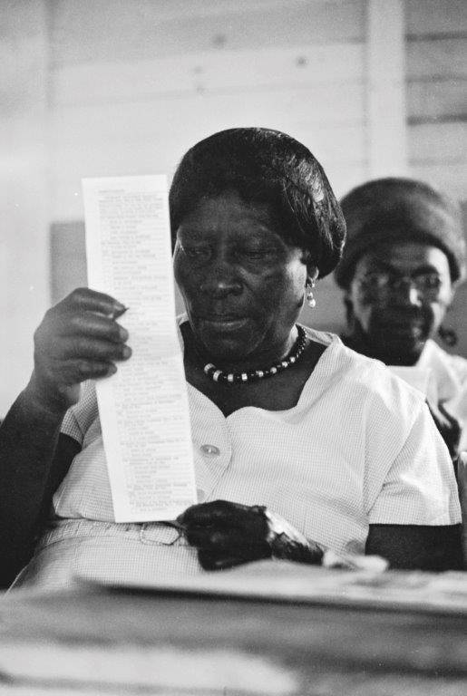 Black-and-white photo of a Black woman reading a sample ballot during a class for new voters at an Alabama church in 1966. Civil rights groups held classes in Alabama and Mississippi about voting and registration after the enactment of the Voting Rights Act.