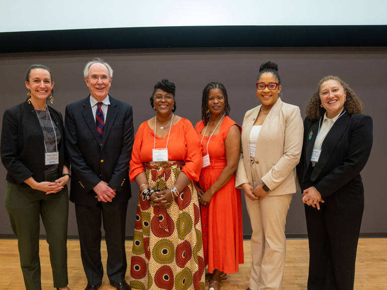 “History Is a Call to Action: Building the Record and Imagining the Future” panelists Kayla Jenkins, Jack Boger, Danita Mason-Hogans, Renée Alexander Craft, Karla McKanders, and Leah Aden stand in front of a neutral gray wall at the SOHP Spring Symposium.