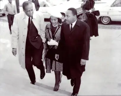 Black-and-white photo of Butler T. Henderson, Coretta Scott King, and Martin Luther King Jr. walking up steps outside.