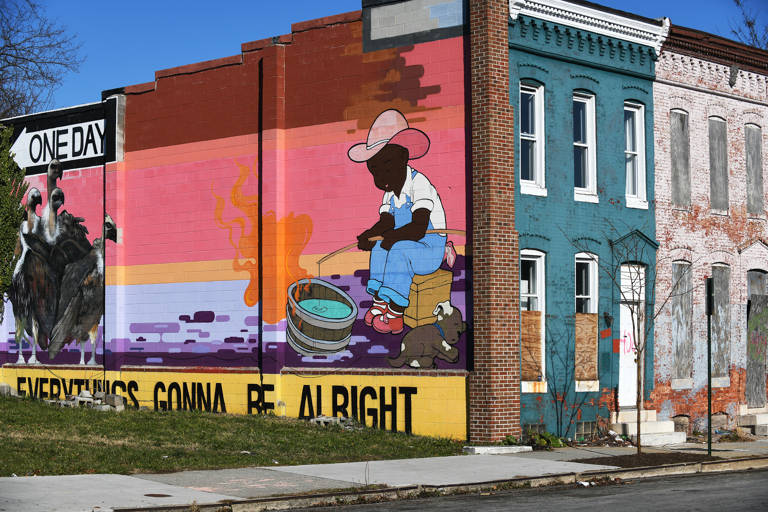 Color photo of a mural of a Black boy fishing and the text "Everything's gonna be alright" painted on the exterior wall of a boarded-up rowhouse in Baltimore, Maryland.