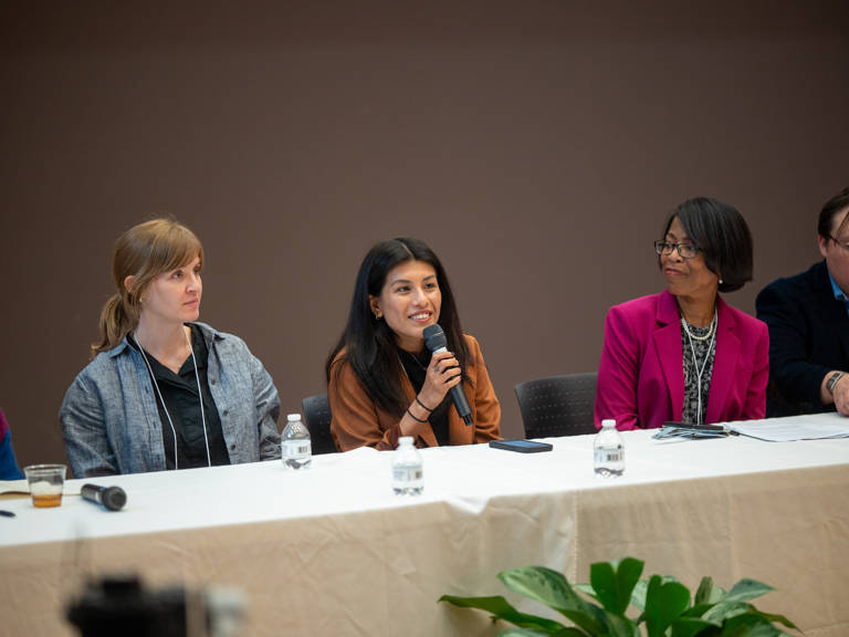 Kimberly Villafuerte Barzola speaks into a microphone during the panel “Documenting the Good Fight: How LDF Stories Are Selected, Collected, and Preserved” while fellow panelists Susie Penman and Melody Hunter-Pillion listen.