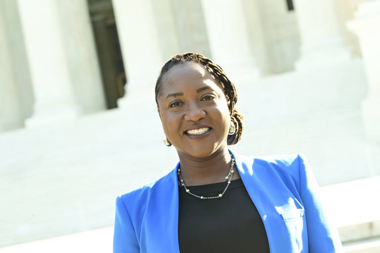 Color photo of Janai Nelson, LDF's President and Director-Counsel, standing in front of the Supreme Court building, wearing a blue blazer.