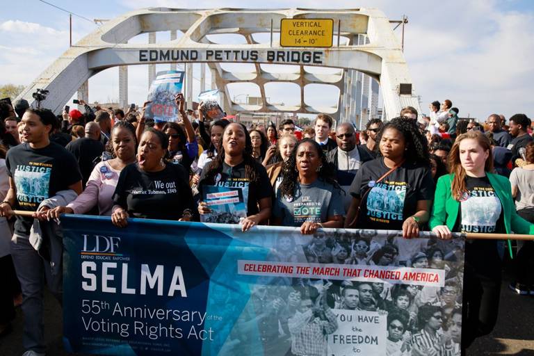 Color photo of LDF President and Director-Counsel Janai Nelson (center) and past LDF President and Director-Counsel Sherrilyn Ifill (third from right) marching across the Edmund Pettus Bridge along with members of LDF's staff on the 55th anniversary of the march from Selma to Montgomery. 