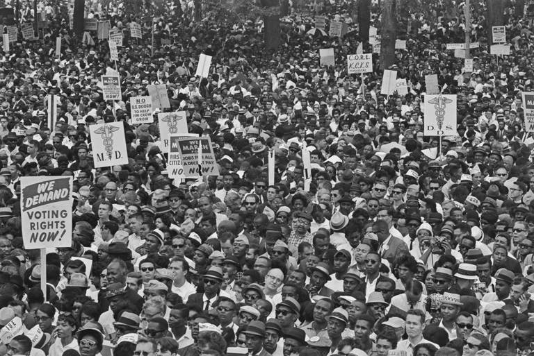 Black-and-white photo of a large crowd of demonstrators, some holding placards, at the March on Washington for Jobs and Freedom in Washington, D.C., on August 28, 1963.