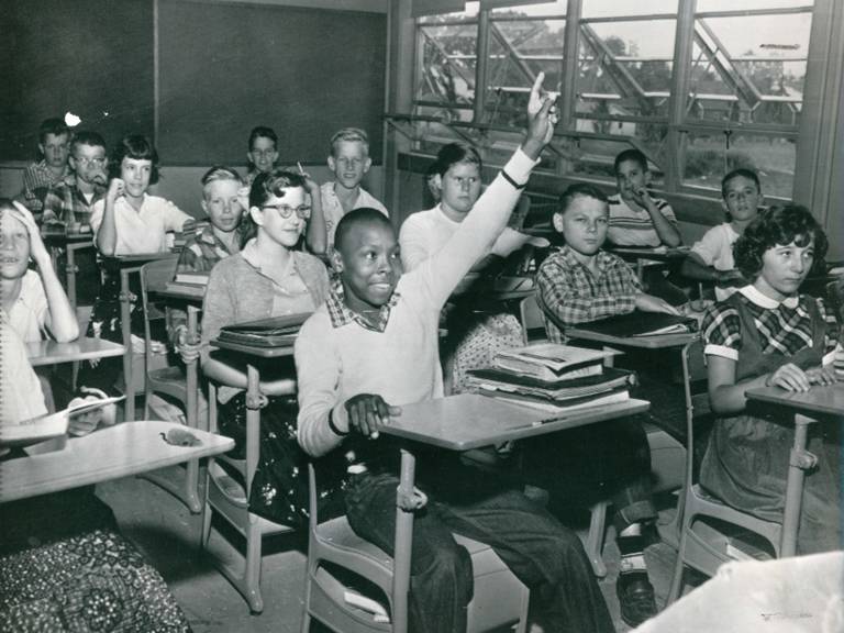 Black student raises hand in integrated classroom.