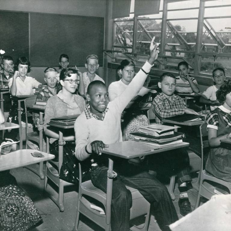 Black student raises hand in integrated classroom.