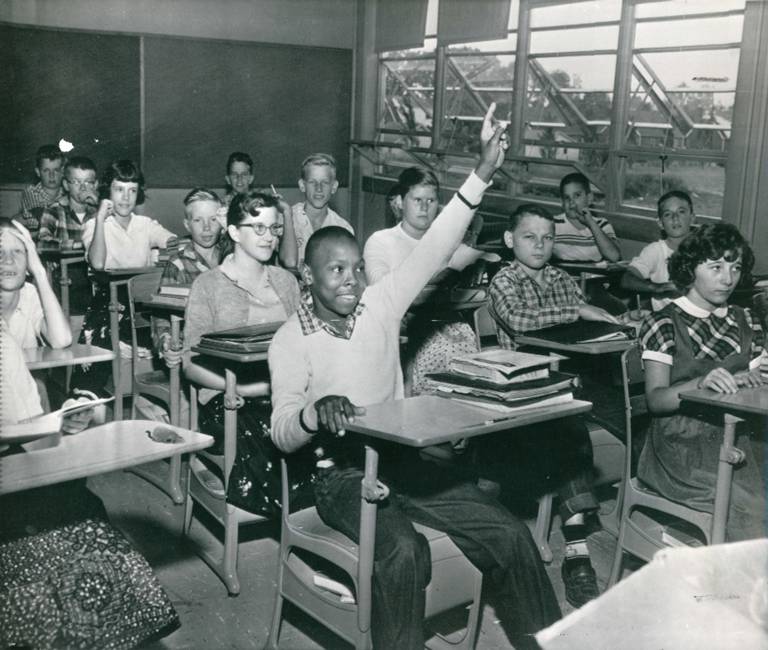 Black student raises hand in integrated classroom.
