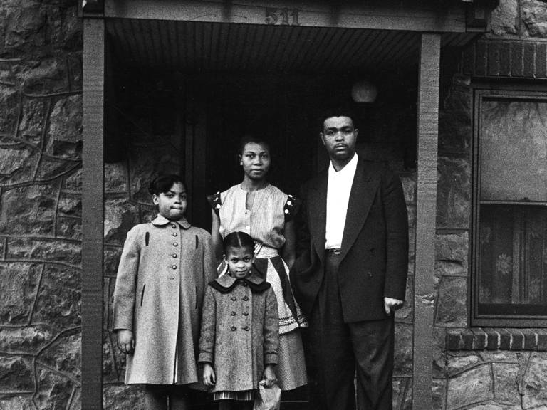 Black-and-white photo of a man, a woman, and two children standing outside a house.