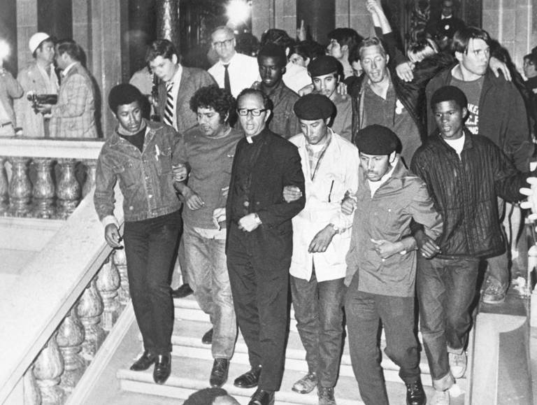 Black-and-white photo of Father James Groppi (third from left) leading a group of welfare demonstrators from the Wisconsin state capitol, after some 300 demonstrators occupied the State Assembly for nearly 10 hours before leaving peacefully.