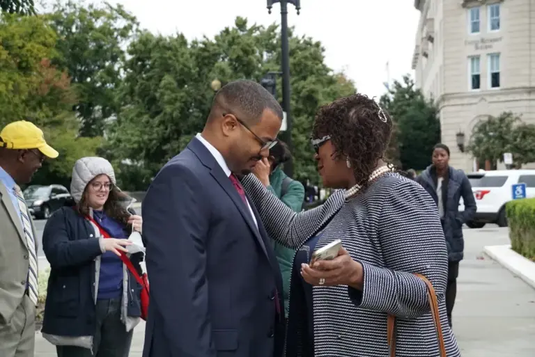 Color photo of LDF Senior Counsel Deuel Ross and plaintiff Letetia Jackson speaking with each other outside before oral arguments, as other people stand in the background.