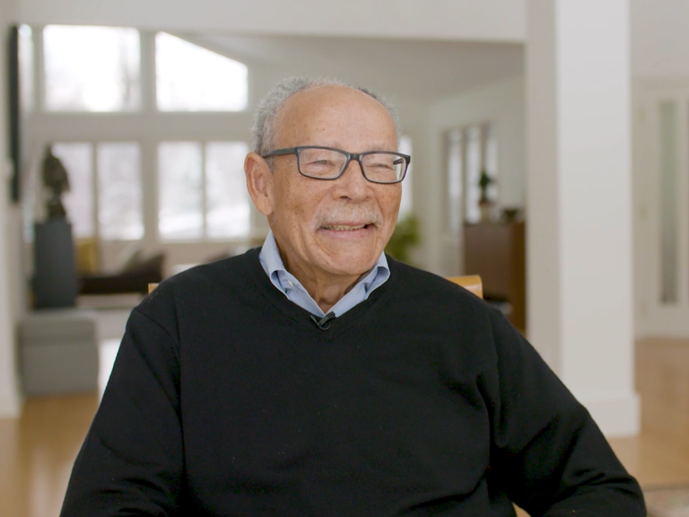 Color photo of O. Peter Sherwood, smiling and seated indoors during his oral history interview.