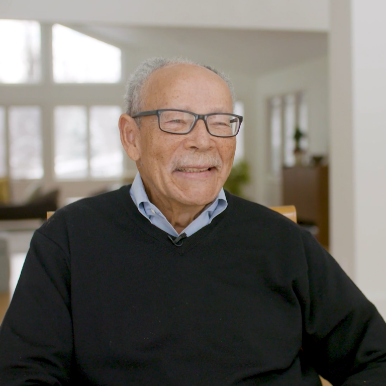 Color photo of O. Peter Sherwood, smiling and seated indoors during his oral history interview.