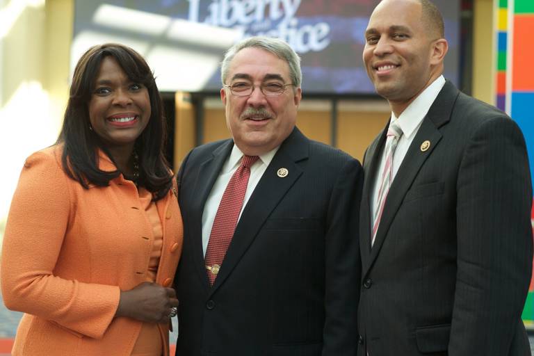 Color photo of G.K. Butterfield wearing a suit and standing between two colleagues at the Congressional Black Caucus’ 45th Annual Legislative Conference. 