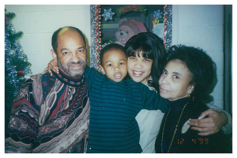 Color photo of Kemba Smith (second from right) surrounded by her parents and a little boy who has his arms around them.