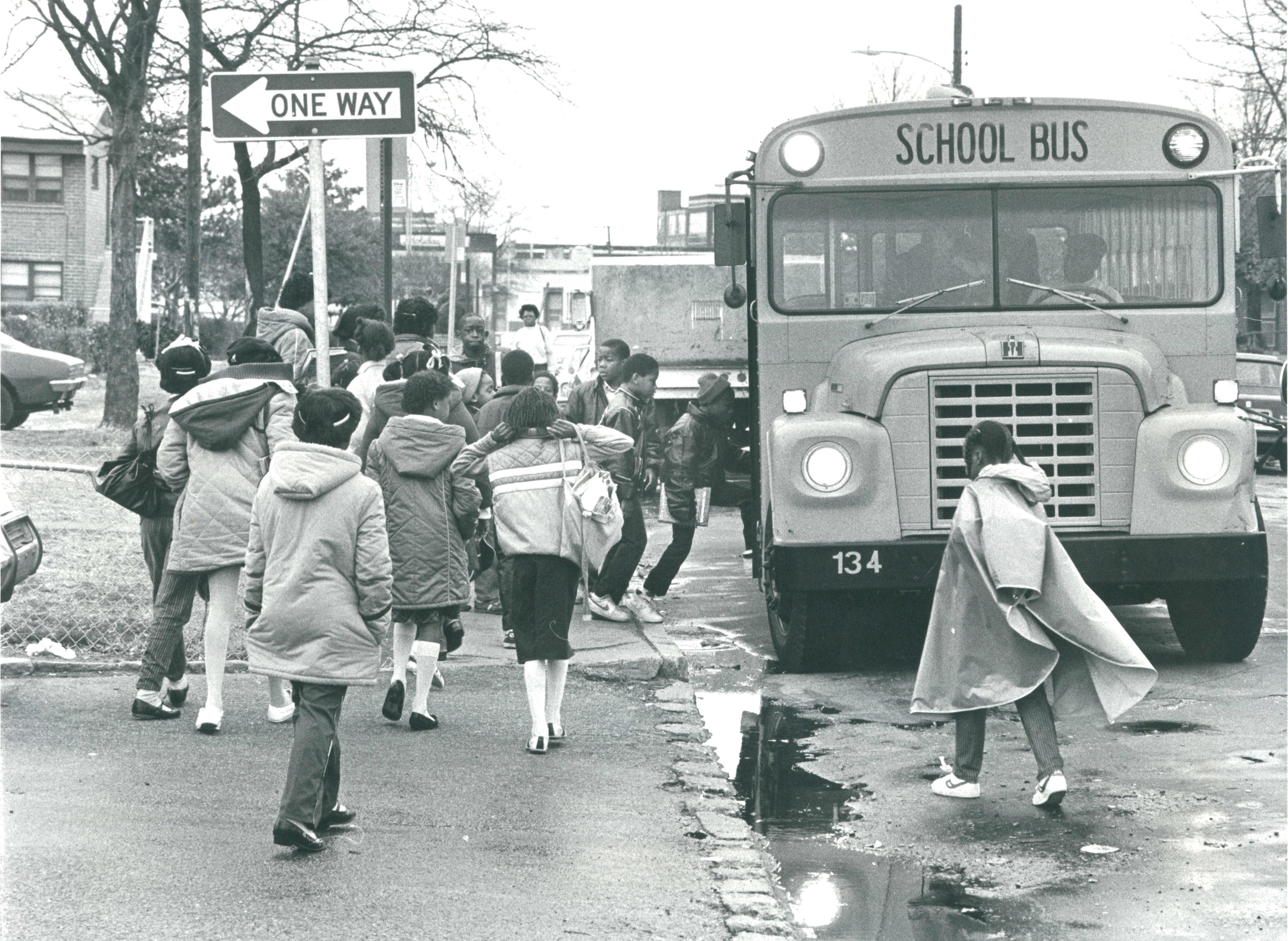 Black children board a school bus.
