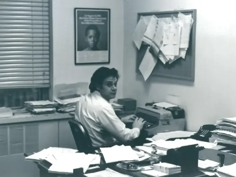 Black-and-white photo of Melvyn Leventhal sitting at his desk typing on a typewriter.