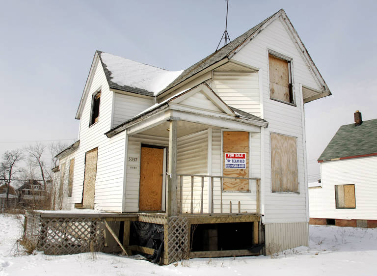 Color photo of a boarded-up white house with a for sale sign on February 14, 2008, in Detroit, Michigan.