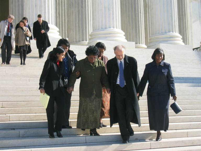 Color photo of the LDF litigation team walking down the Supreme Court steps with a client. 