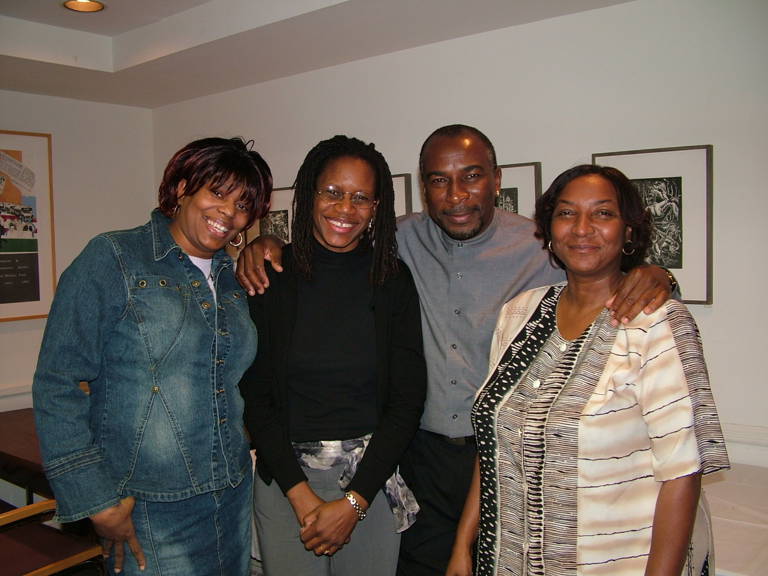 Color photo of four members of the Wright family standing in a room with their arms around each other.