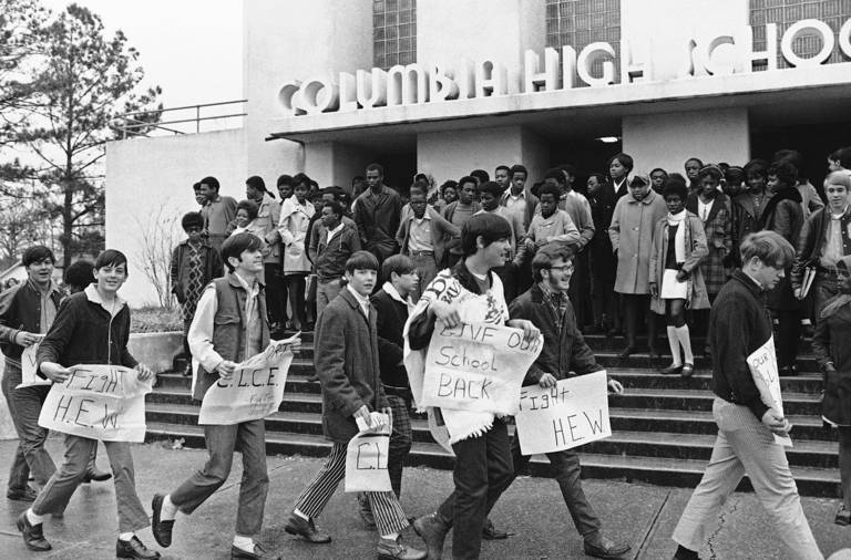 Boycotting white students walking outside Columbia High School in Mississippi while Black students wait to attend classes.