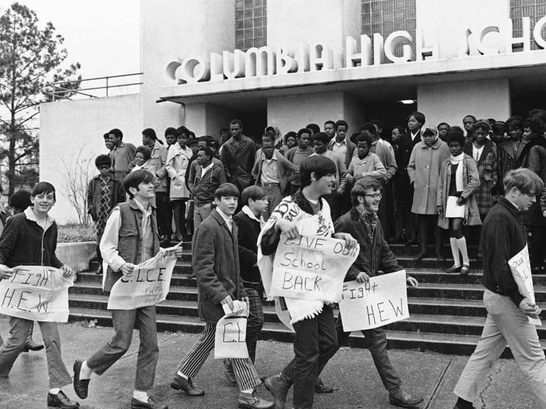 Boycotting white students walking outside Columbia High School in Mississippi while Black students wait to attend classes.